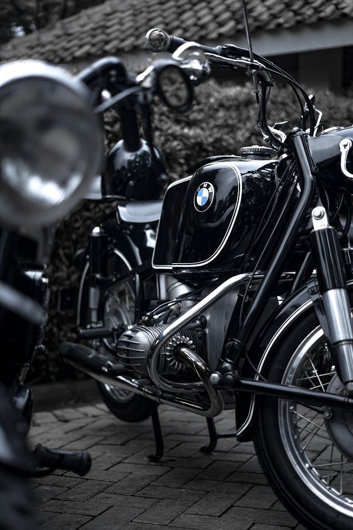 A classic black motorcycle parked outdoors on cobblestone, showcasing its vintage design.