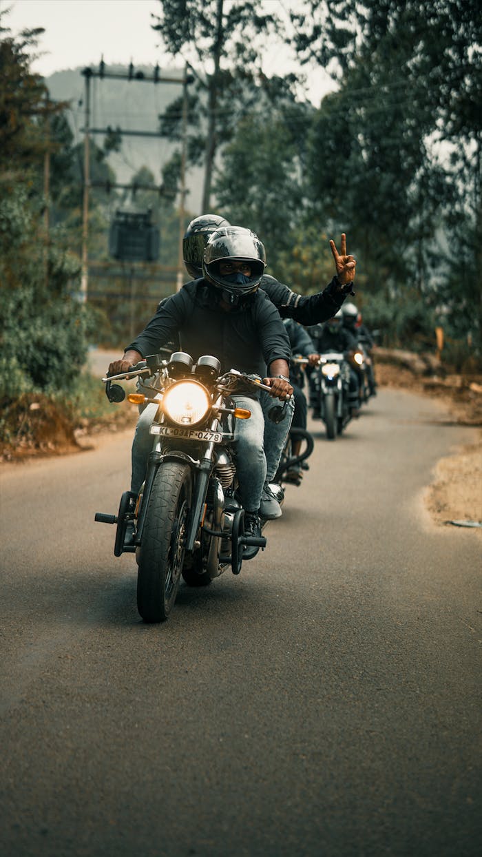 A group of bikers wearing helmets rides motorcycles on a scenic road, enjoying an adventurous trip.
